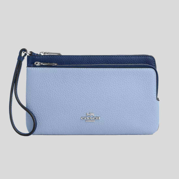Blue Coach wristlet with a strap on a gray background
