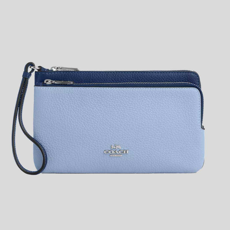 Blue Coach wristlet with a strap on a gray background